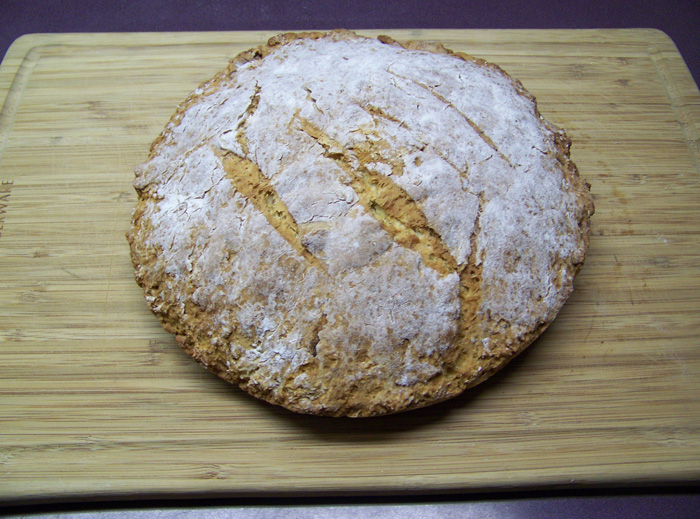 A loaf of soda bread on a wooden surface.