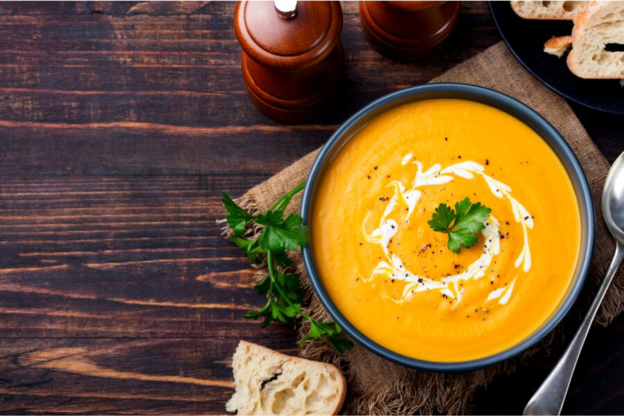 A bowl of pumpkin soup decorated with parsley and cream.