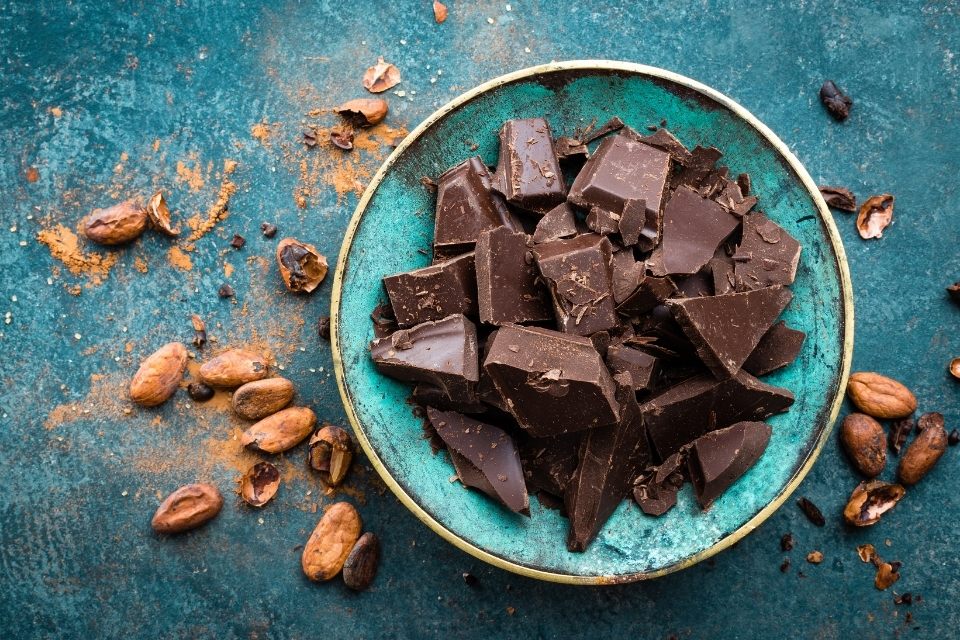 Chocolate negro en un cuenco rodeado de semillas de cacao.