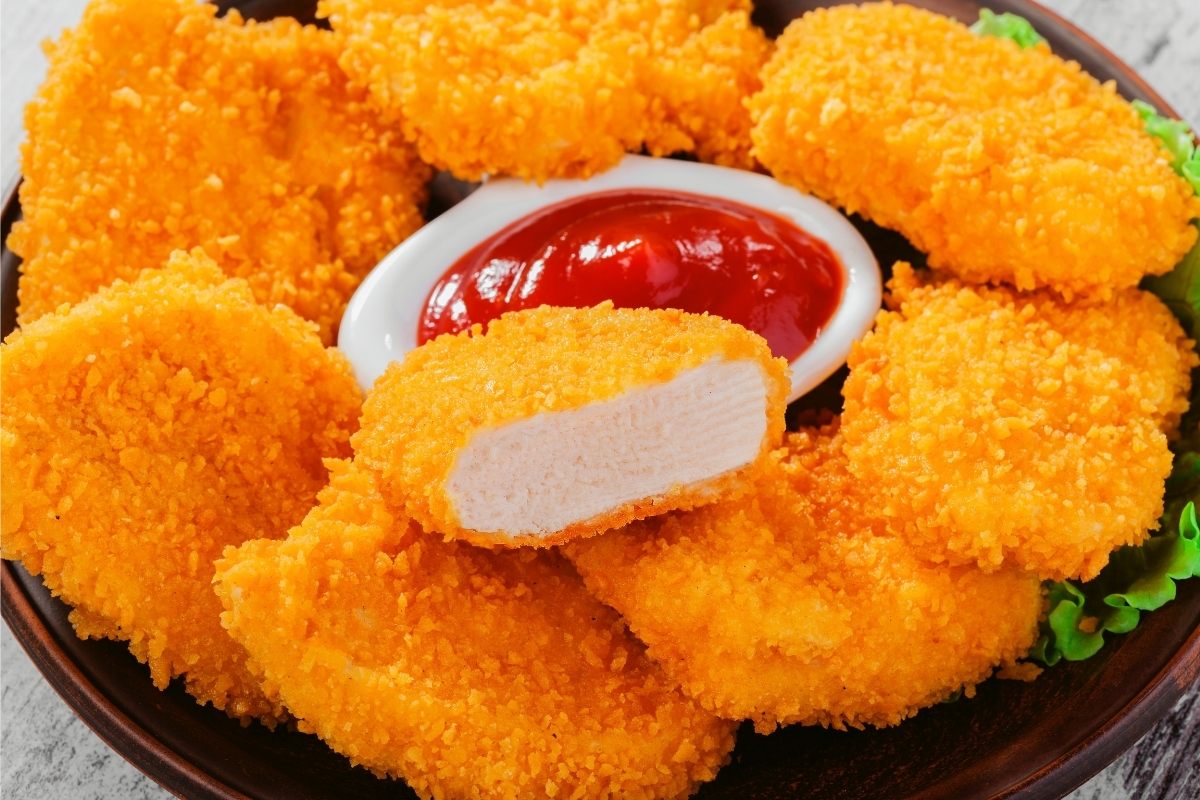 A plate of chicken nuggets with tomato sauce, in a small bowl, in the middle.