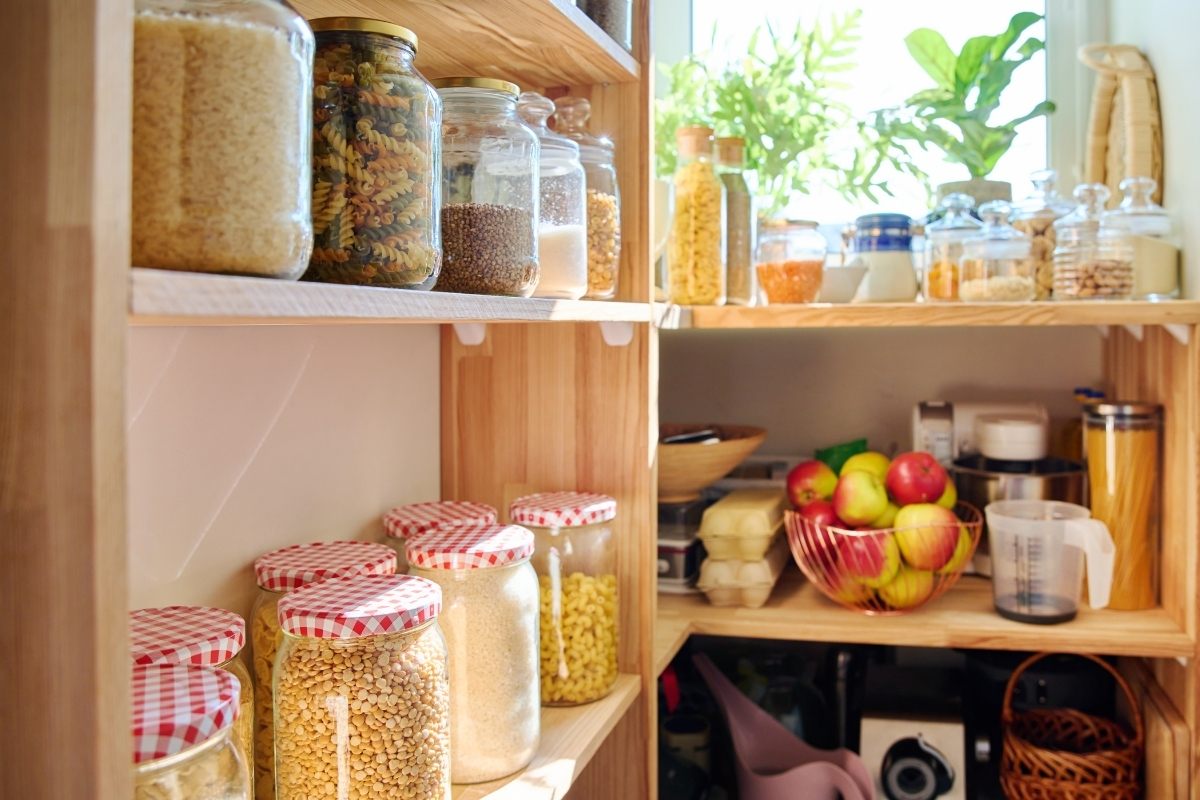 Pantry with food stored in glass jars placed on shelves.