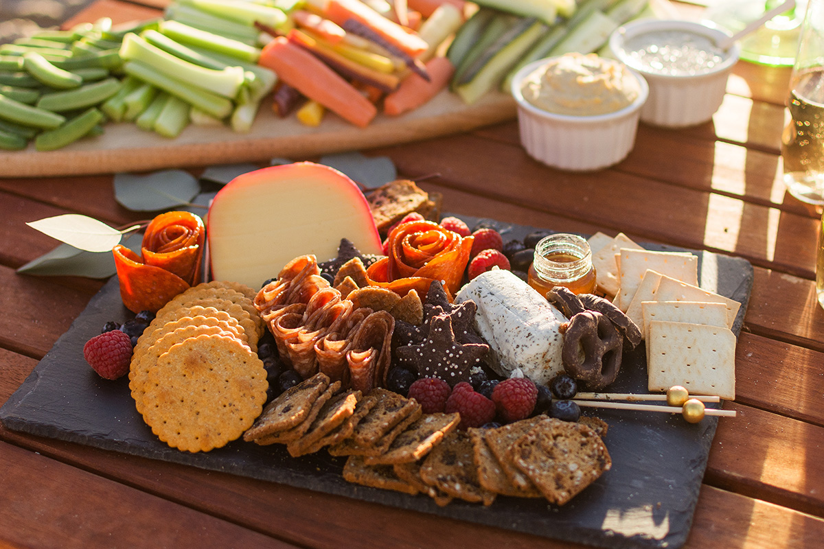 Table set with a grazing board and various appetizers including crudites and dips. 