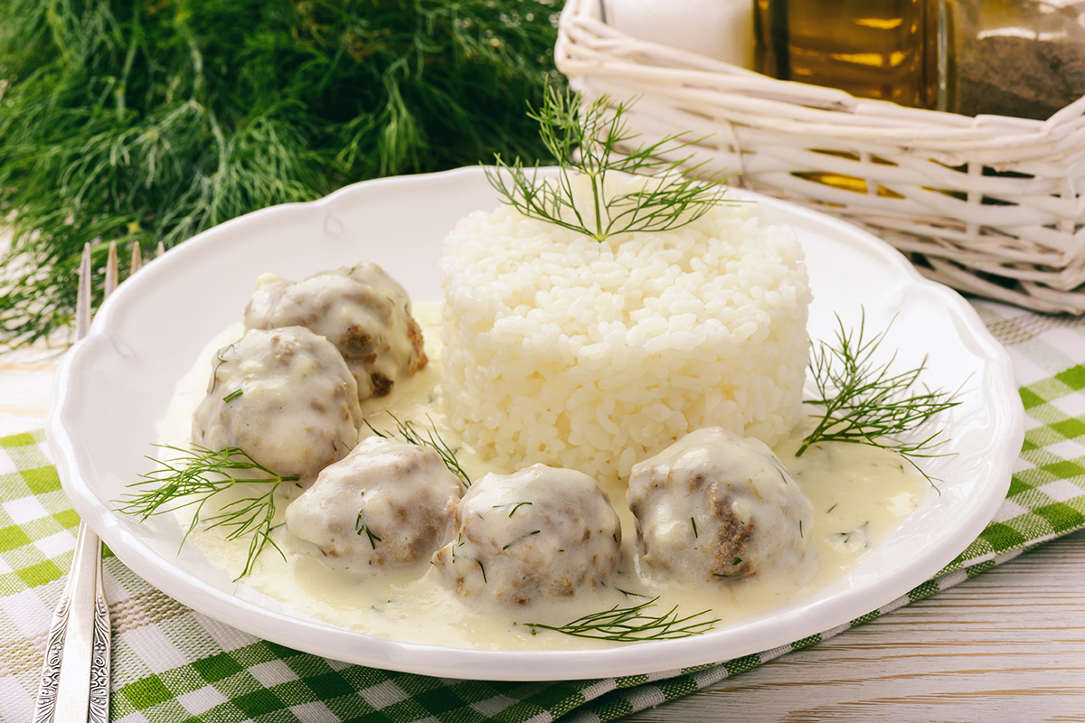 A plate of veal meatballs with white sauce accompanied of boiled rice.