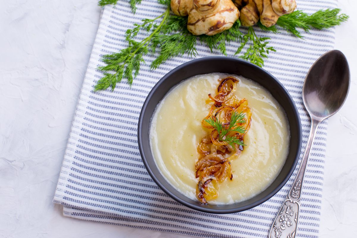 A bowl of Jerusalem artichoke soup garnished with crunchy onion.