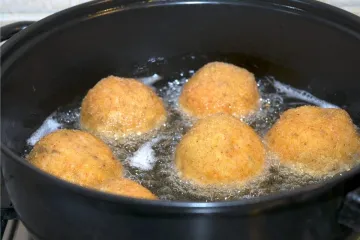Croquetas de arroz, o arancini, friéndose.