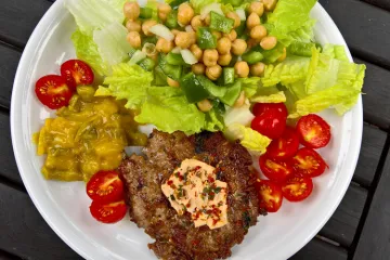 Hamburguesa de cordero con salsa de queso, piriñaca, lechuga y picalilli.