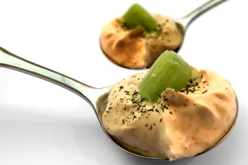Dos cucharas con crema de melocotón con kiwi.