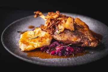 Ganso asado glaseado con miel y hierbas acompañado de patata y lombarda.