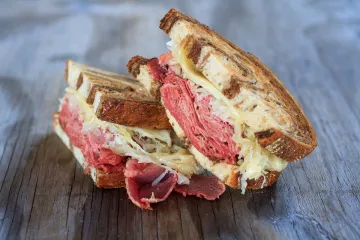 Bocadillo Reuben con corned beef ahumado, queso y sauerkraut.