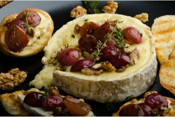 Queso brie hornado con nueces y uvas.