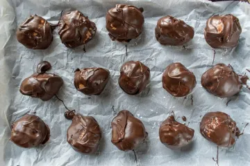 Bolas de mantequilla de cacahuete y chocolate secándose sobre papel parafinado.