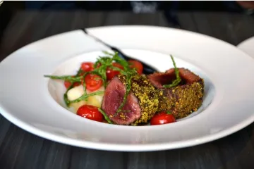 Carne de caballo poco hecha servida con mostaza y guarnición.