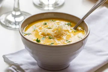Sopa de calabaza decorada con hierbas y queso rallado.