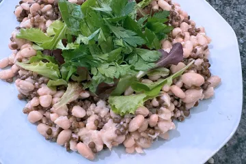 Ensalada de legumbres con lentejas, alubias blancas, hojas variadas, perejil y una vinagreta a la cebolla.