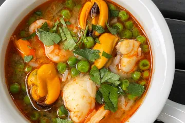 Un cacillo de loza con sopa de pescado y marisco.