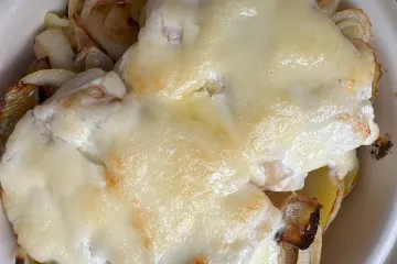 Detalle de bacalao al horno con mayonesa en una cazuela de barro.