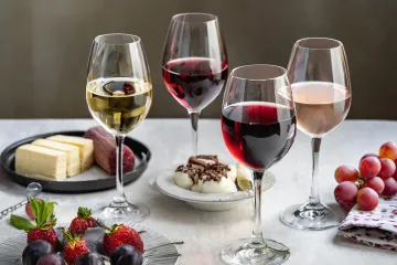 Copas con distintos tipos de vino y varios postres sobre una mesa.