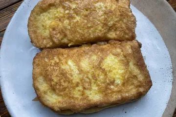 Un plato con dos emparedados de jamón serrano recién fritos.