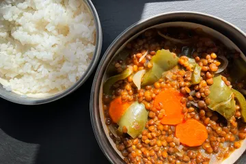 Lentejas con verduras en un cuenco y acompañadas con arroz blanco.