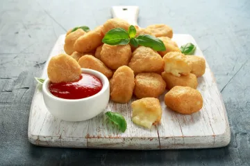 Bolitas de mozzarella rebozadas y fritas servidas con kétchup.