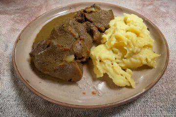 Un palto con carne guisada acompañ1ado de su salsa y puré de patata.