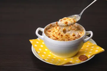 Una taza con crema de cebolla gratinada.