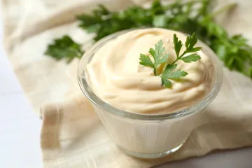 Un cuenco con mayonesa, o mahonesa, decorada con perejil.