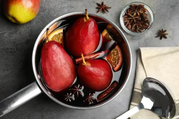 Un cazo con peras al vino tinto y sus aromatizantes.