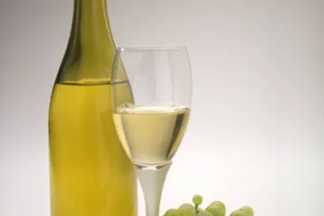 Una botella de vino blanco y uvas.