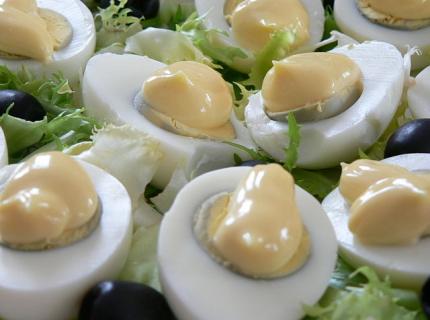 Huevos rellenos cubiertos con mayonesa.