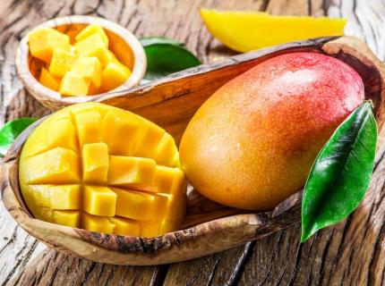 Un mango entero y medio mango cortado en una cesta.