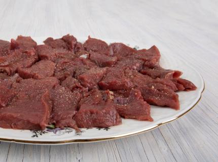 Un plato con carne cruda de ciervo, cortada y condimentada.