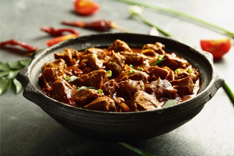 Un plato hondo con un curry roganjosh de cordero.