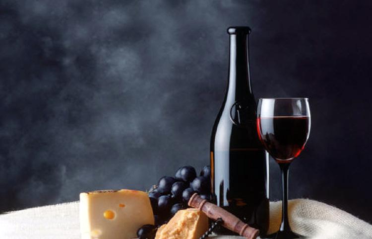 Botella, copa de vino tinto, uvas y queso.