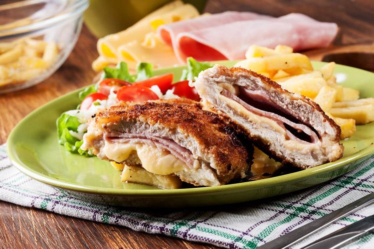 San Jacobo de cerdo abierto, servido con ensalada y patatas fritas.