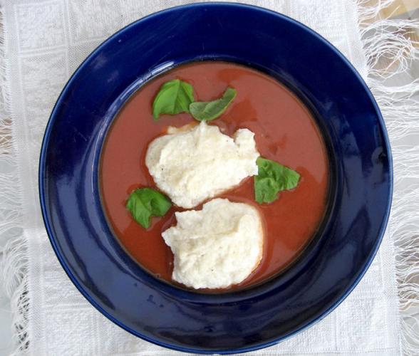 Sopa alemana de tomate decorada con queso crema y albahaca fresca.