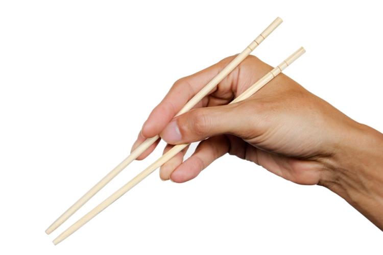 Una mano sujetando un par de palillos de madera.