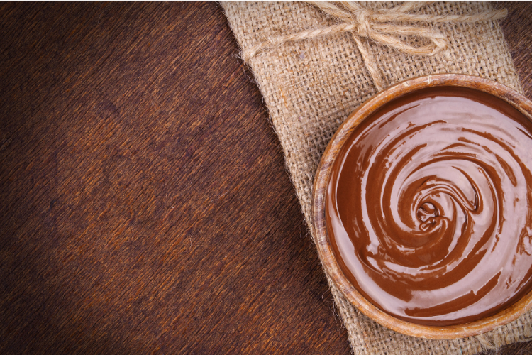 Crema de chocolate en una tarrina individual sobre una servilleta rústica.