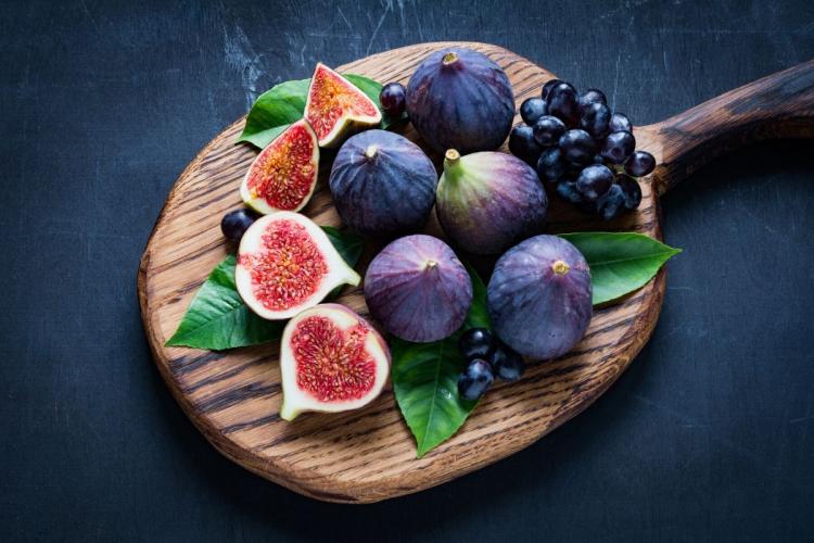 Higos frescos maduros y uvas tintas sobre una tabla de cortar.