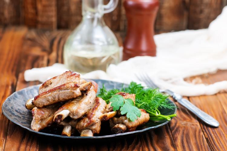 Chuletas pequeñas fritas con hierbas en un plato.