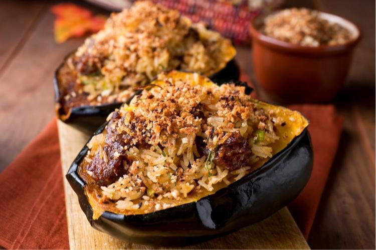 Dos mitades de calabaza rellena con salchicha y arroz.