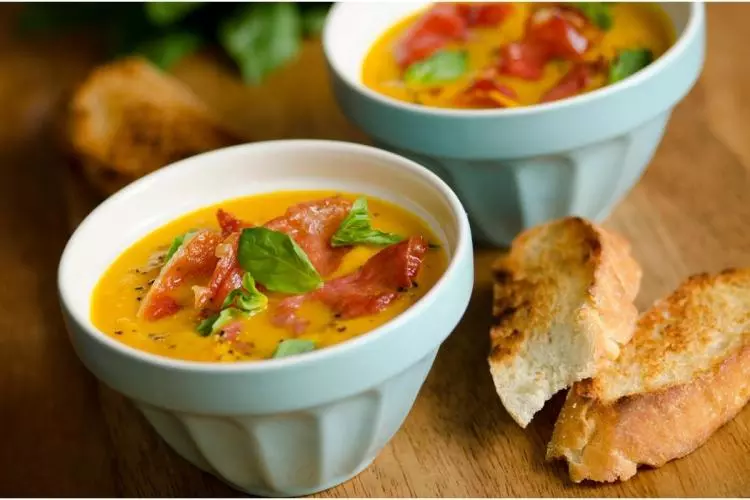 Sopa fría de melón cantalupo decorada con jamón serrano y albahaca, acompañada con pan tostado.
