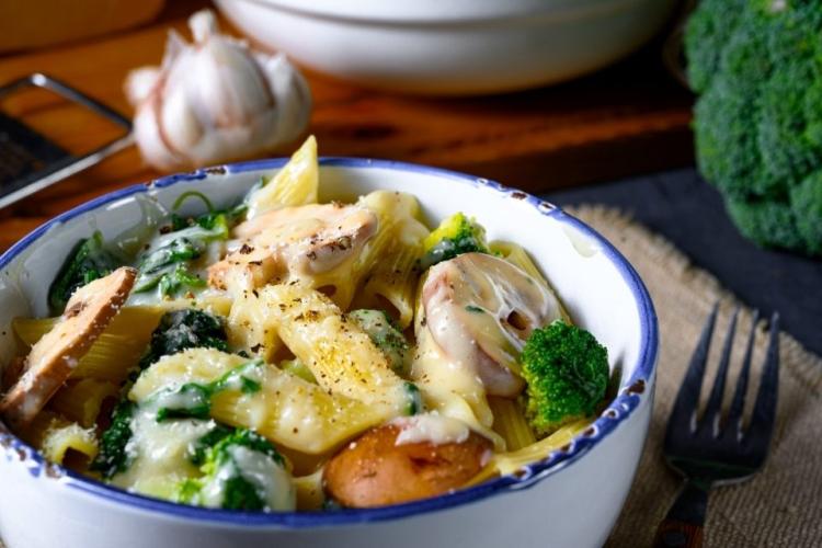 Un recipiente con pasta, brócoli y champiñones.