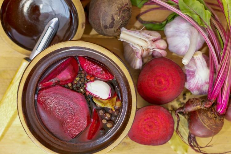 Remolacha encurtida en recipiente de vidrio rodeada de ingredientes.