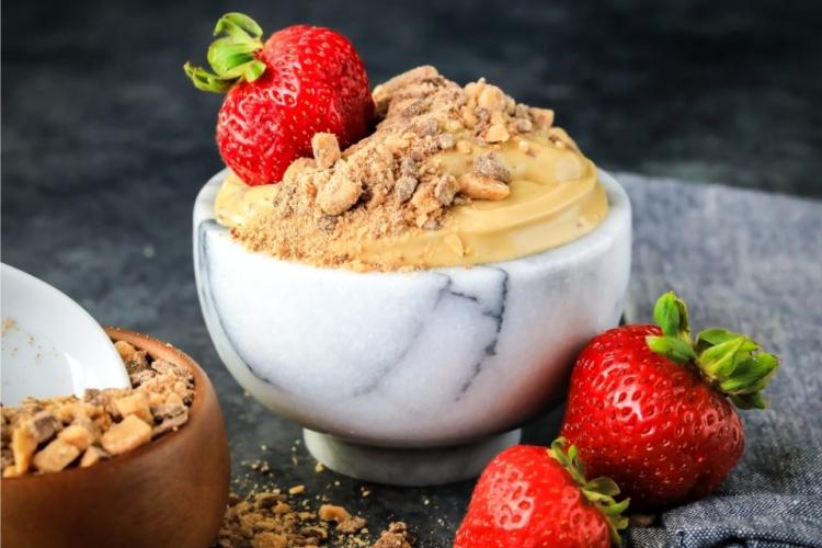 Un cuenco con crema de queso al tofe y fresas frescas.