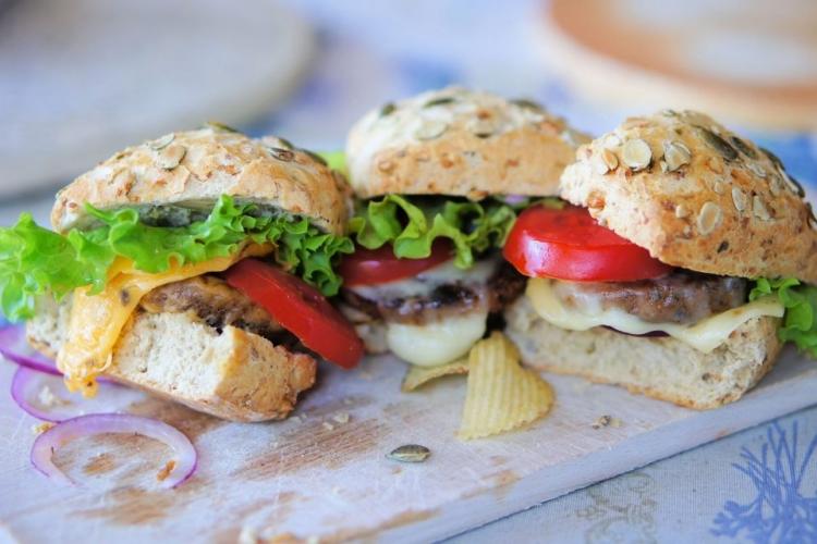 Tres hamburguesas de insectos con queso y ensalada en sus bollos.