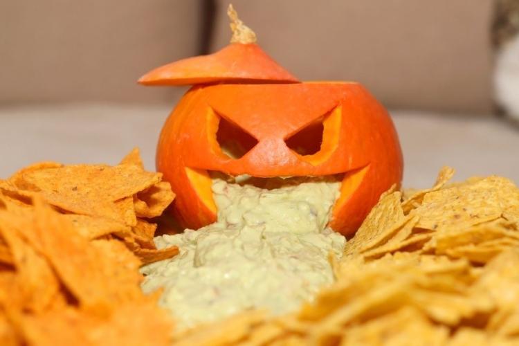 Triángulos de maíz con salsa de queso para mojar en presentación Halloween.