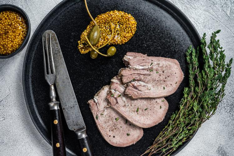 Lonchas de lengua de ternera hervida acompañadas con mostaza.