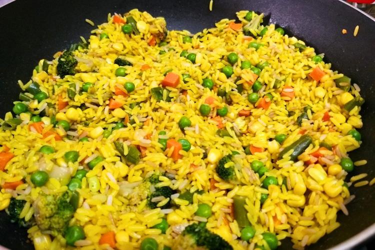 Arroz al azafrán con verduras en una sartén.