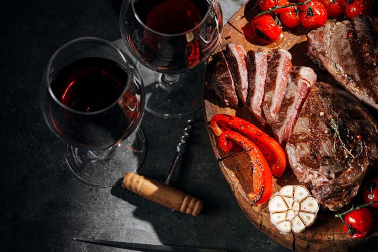 Comida para dos con filetes y vino tinto.